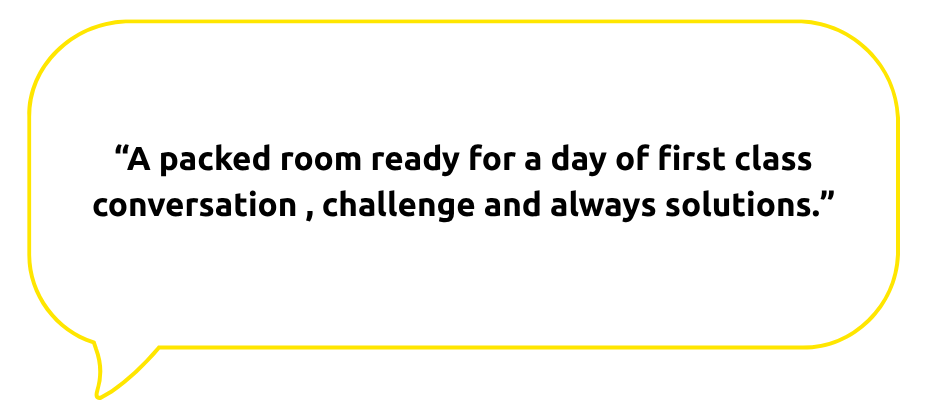 A speech bubble with an orange outline contains the quote: “A packed room ready for a day of first class conversation, challenge and always solutions.”